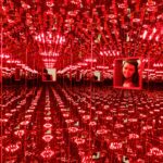 Student looking through small window into red infinity mirrors