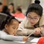 Tesia Fan Tong, a 2+2 education student in a partnership between Brenau and Anhui Normal University in China, works with a first grader on developing her story for "Tiger Tales" at Fair Street International Academy on Friday, Feb. 2, 2018. (AJ Reynolds/Brenau University)
