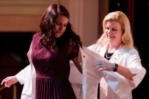 Nursing student Victoria Coker receives her white coat from Dina Hewett, director of the Mary Inez Grindle School of Nursing. (AJ Reynolds/Brenau University)