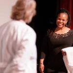 Nursing student smiles while holding her white coat