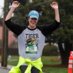 woman cheers as she runs with her hands up