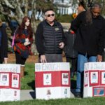 Debra Dobkins, Jay Andrews and Chet White stand with posters remembering the victims of the mass shooting at Marjory Stoneman Douglas High School. Brenau students, staff and faculty gathered around the Grace Hooten Moore Memorial Fountain and read the names of each victim after a bell rang from Grace Episcopal Church in memory. (AJ Reynolds/Brenau University)