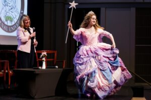 "Glinda," or Brenau acting major Rachel Finazzo, glides across the stage during Women's Leadership Colloquium on Friday, March 15. (AJ Reynolds/Brenau University)