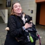 A service dog licks Tammy Buck during the symposium.