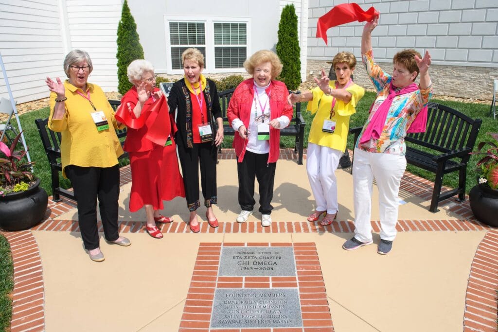 Alums stand in front of terrace.