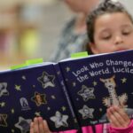 An elementary school student reads from the book.