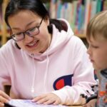 A college student and elementary school student read to each other. 1