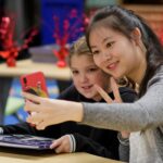 A college student takes a selfie with an elementary school student.