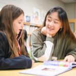 An elementary school student and college student read to each other.