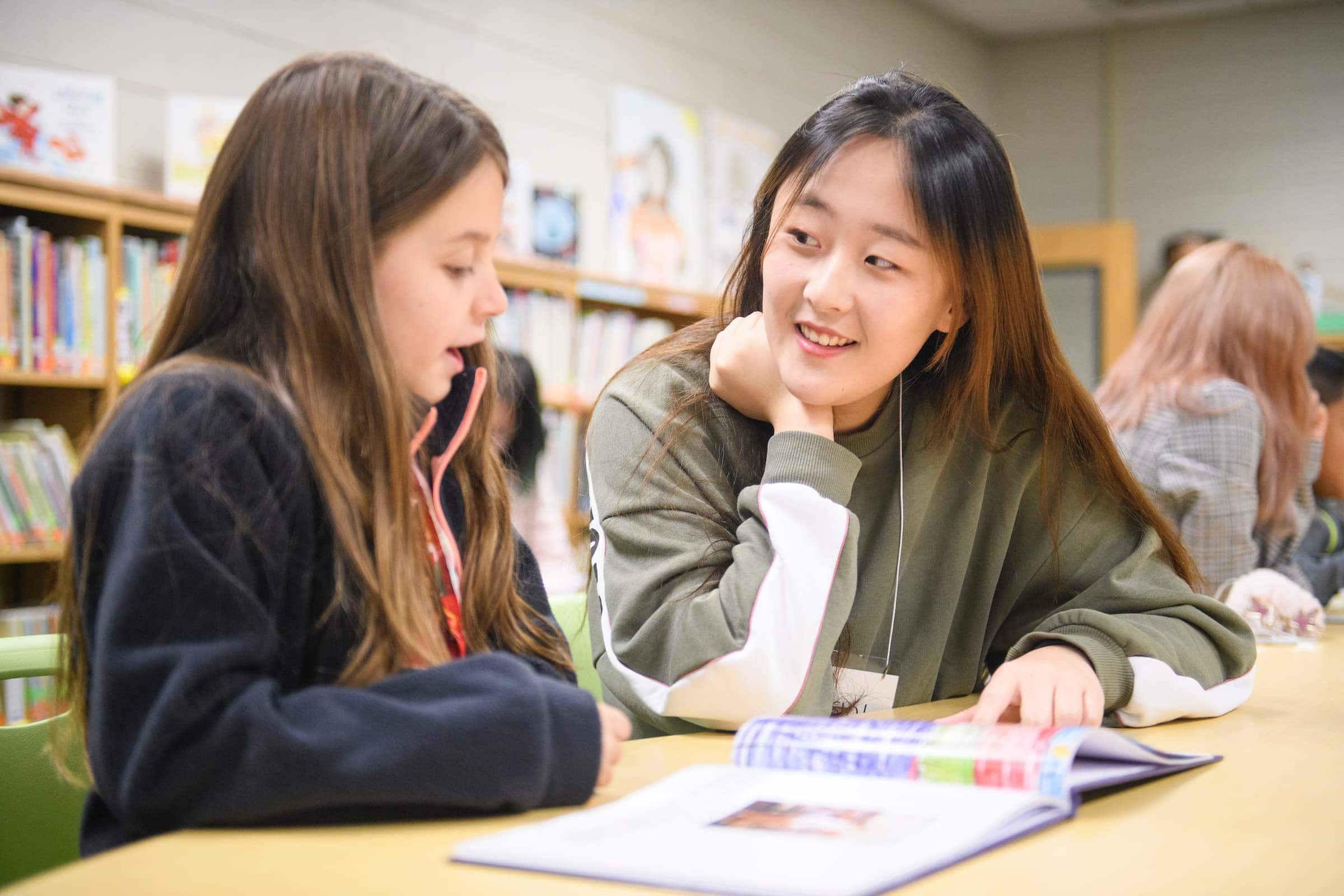 An elementary school student and college student read to each other.