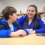 A college student and elementary school student read to each other. 2