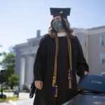 A graduate in a cap and gown receives her diploma cover