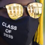 A graduate in regalia as Pearce Auditorium reflects in her sunglasses