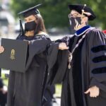 A graduate and the university president elbow bump