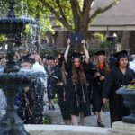 A graduate celebrates with her diploma as the graduates walk toward the fountain at the conclusion of the Women's College Commencement at Brenau University Friday May 4, 2018 in Gainesville, Ga. (Jason Getz for Brenau University)