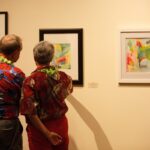 Two attendees study some of the artwork of Lyndrid Patterson while making their way through the exhibition.