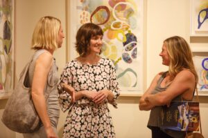 Erin McIntosh chats with friends near some of her artword during a reception for the 2018 President's Summer Art Series in the Sellers Gallery at Brenau University.