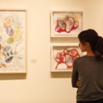 A patron looks at Erin McIntosh's art work based on organic microscopic material.