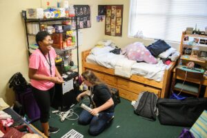 Starr Hart, left, and Clara Woodfield share a laugh while setting up their room. 