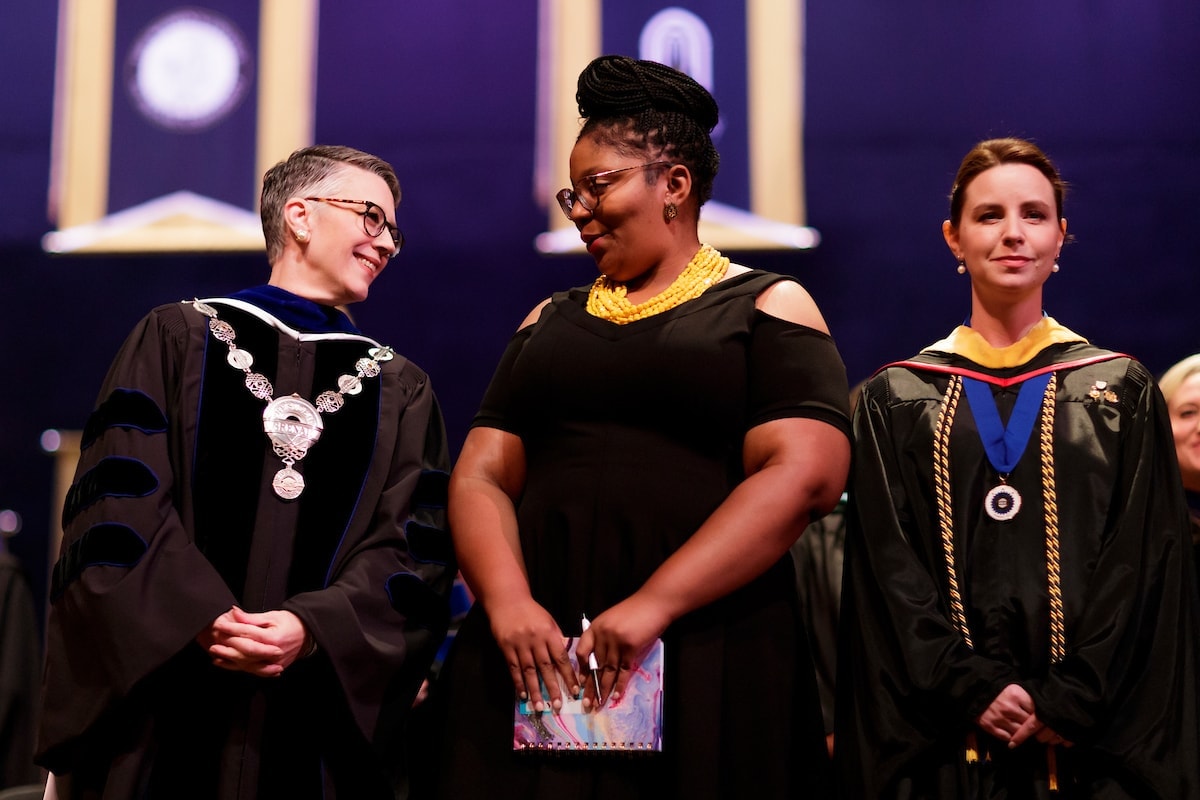 President Anne Skleder, Cierra Franklin and Professor Jessi Shrout stand together on stage during fall convocation.