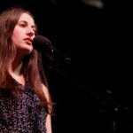 Student speaks into microphone on stage