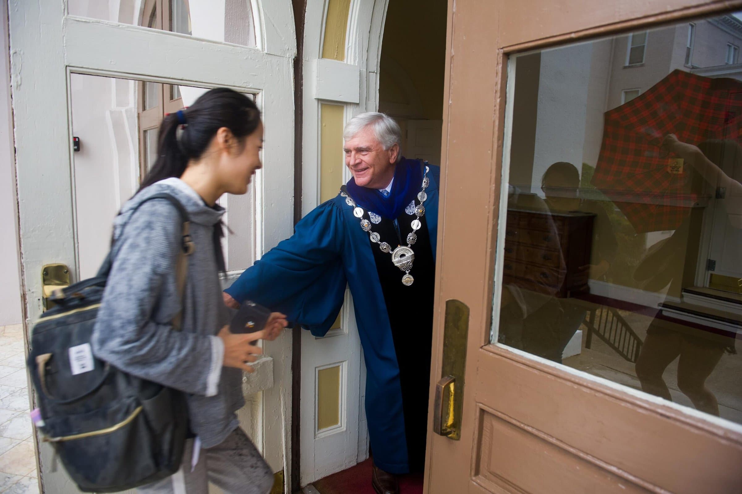 Brenau President Ed Schrader holds the door for students as they make their way out of the rain and into Pearce Auditorium for Brenau's Fall Convocation. (AJ Reynolds/Brenau University)