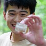 A student tests water at Chicopee Lake.