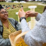 A student receives a gold necklace from a basket