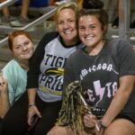 three students pose in the stands