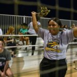 student holding pom poms cheering