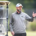 Brenau head coach Damon Stancil standing by golf cart