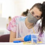 Student with mask on painting