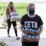 two student carying cans for food drive