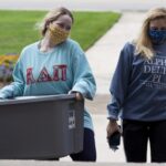 students carrying a container of food