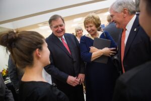 From left to right, Douglas Ivester, Kay Ivester and Brenau President Ed Schrader react to seeing the new scrubs for students of the Mary Inez Grindle School of Nursing during the dedication of the Mary Inez Grindle School of Nursing. (AJ Reynolds/Brenau University)
