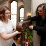 Karen Baker and Dominique Wagner work on decorating the grand staircase at the Callanwolde Fine Arts Center in Atlanta on Tuesday, Nov. 20, 2018. (AJ Reynolds/Brenau University)