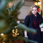 Courtney Wilson works to arrange presents under a tree.