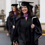 student walking outside with diploma