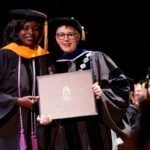 president posing with student as she receives her diploma