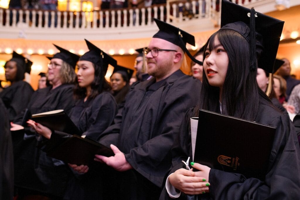 students sit with their diplomas