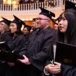 students sit with their diplomas