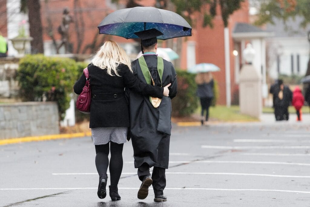 Graduates and their families walk under umbrellas during the Brenau University Graduate Commencement ceremony on Friday, Dec. 14, 2018 in Gainesville, Ga.