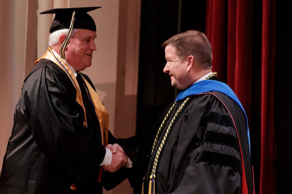 Allan Rollins shakes hands with Jim Eck during the Brenau University Undergraduate Commencement ceremony on Friday, Dec. 14, 2018 in Gainesville, Ga. (AJ Reynolds/Brenau University)