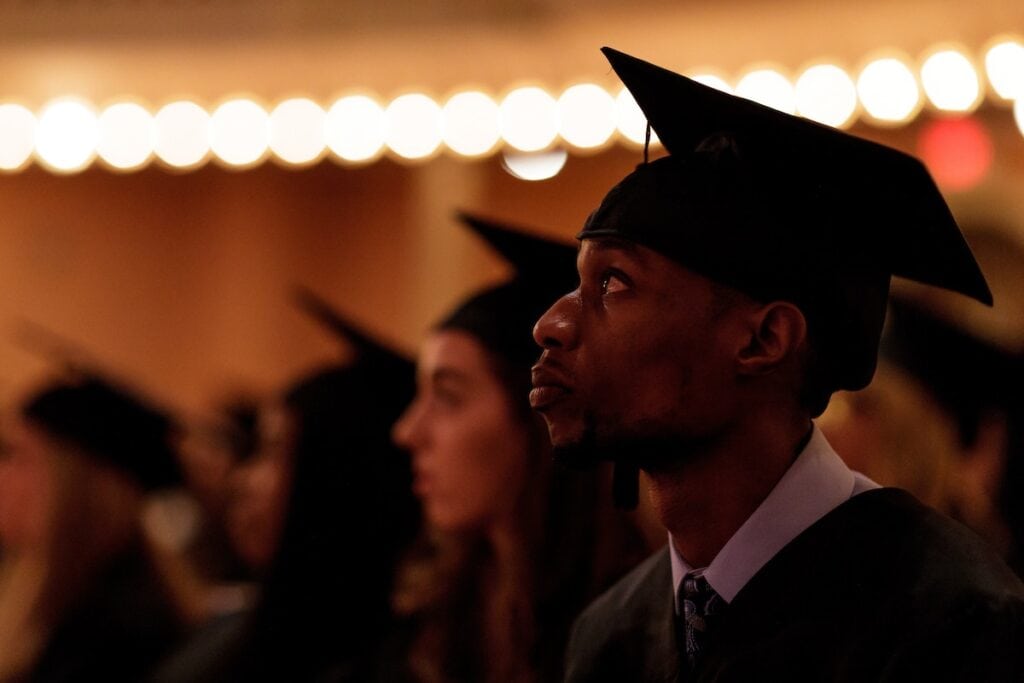 man sitting in audience during graduation