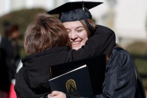 Katlyn Jarrard gets a hug after graduating with her Master of Interior Design degree during the Brenau University graduate winter commencement ceremony. (AJ Reynolds/Brenau University)