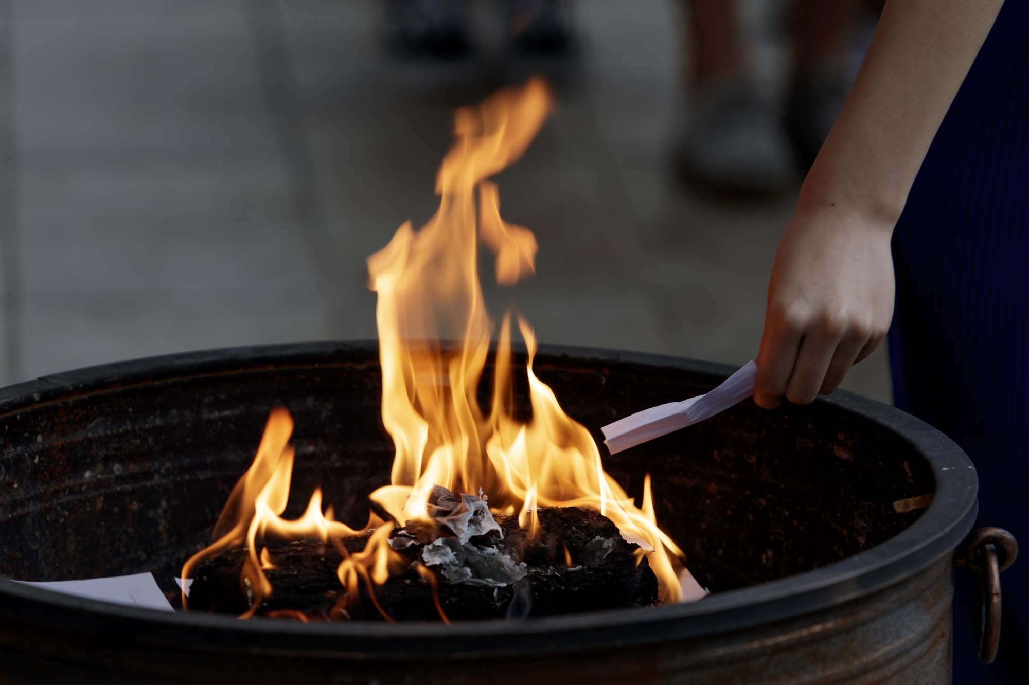 A student drops a sheet of paper into a fire during the Gold Refined By Fire ceremony