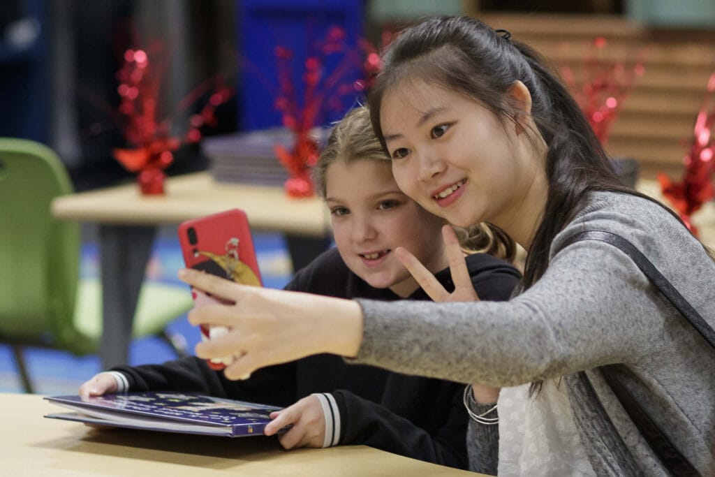 An education student takes a selfie with a child and her Tiger Tales book