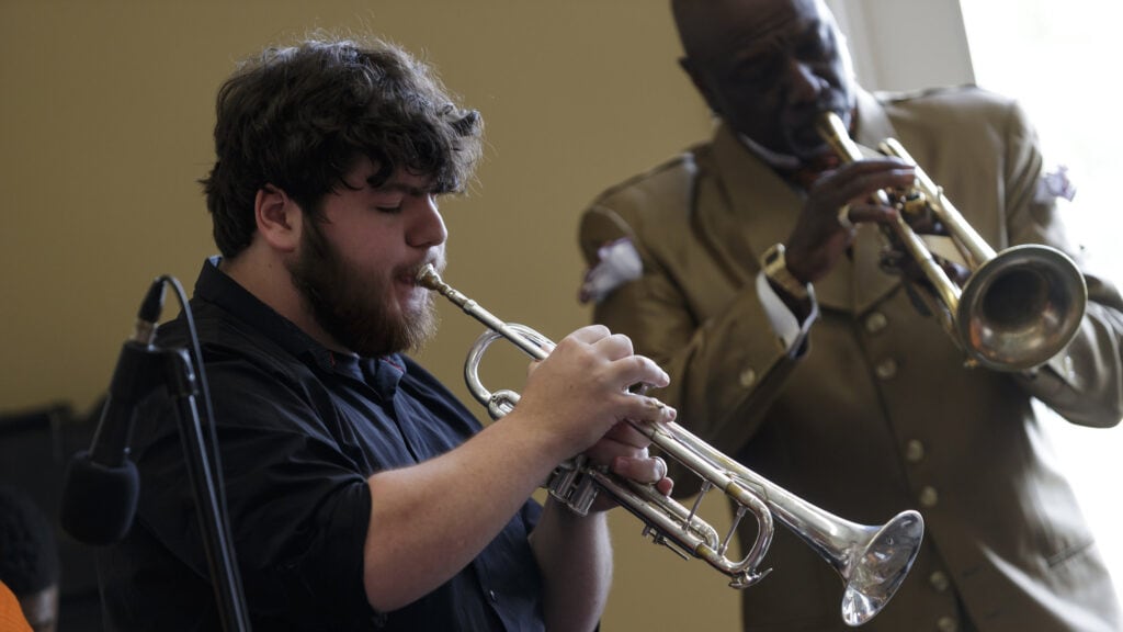 A student plays trumpet along with a professional