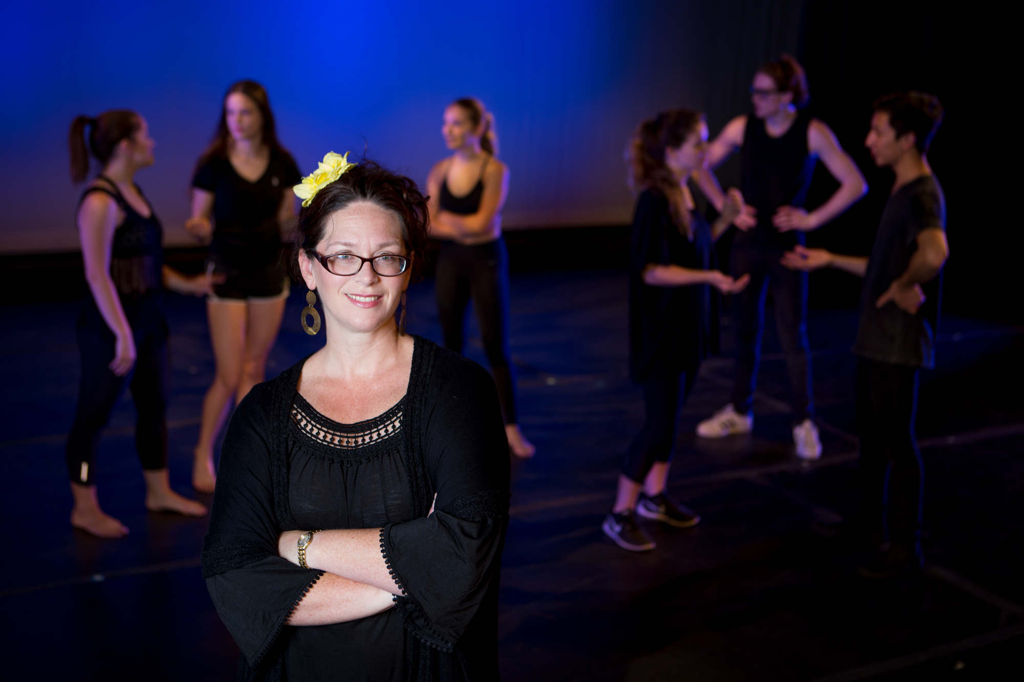 A MAT alumnus and theatre teacher poses for a photo with her students in the background