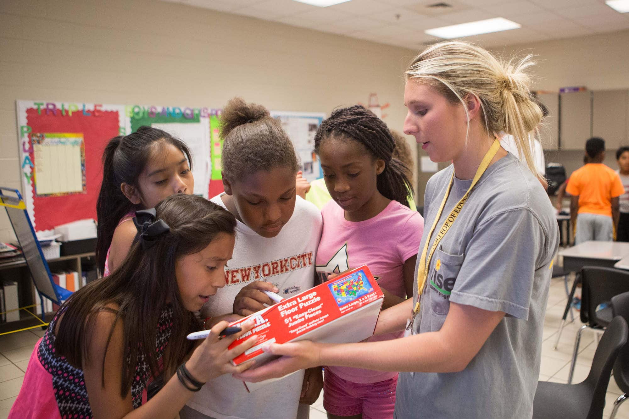 An education student works with middle school aged children inside a classroom